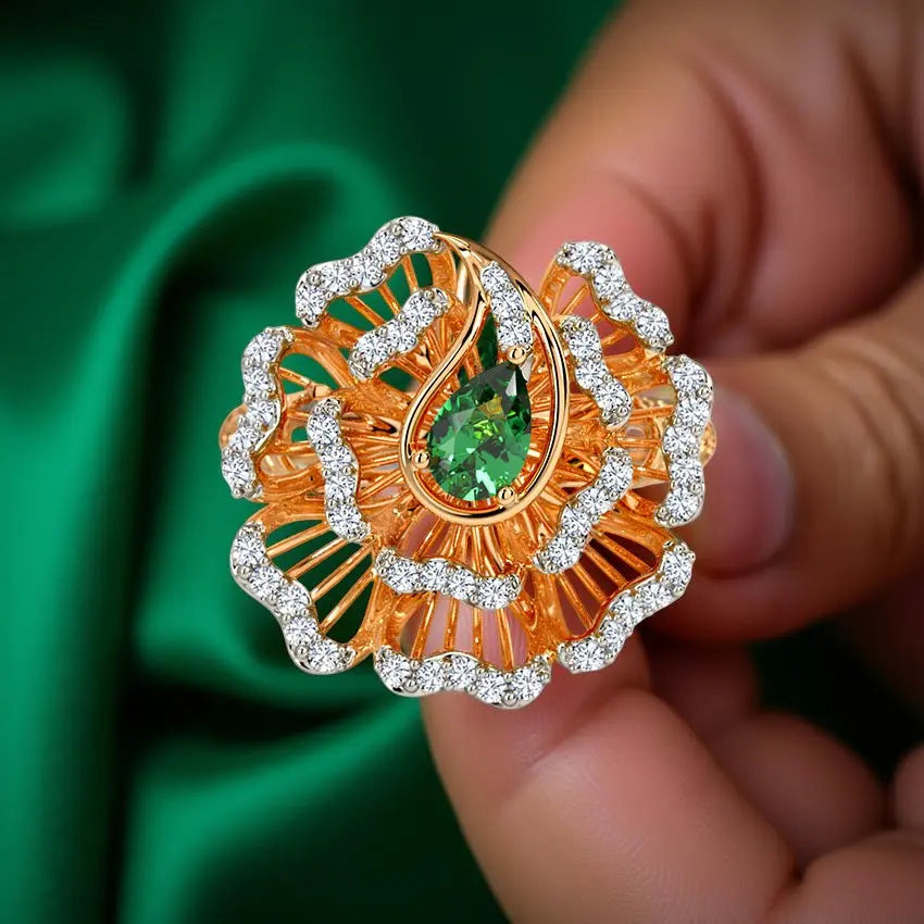 Gold and diamond-encrusted ring with a green gemstone held by a hand against a green fabric background