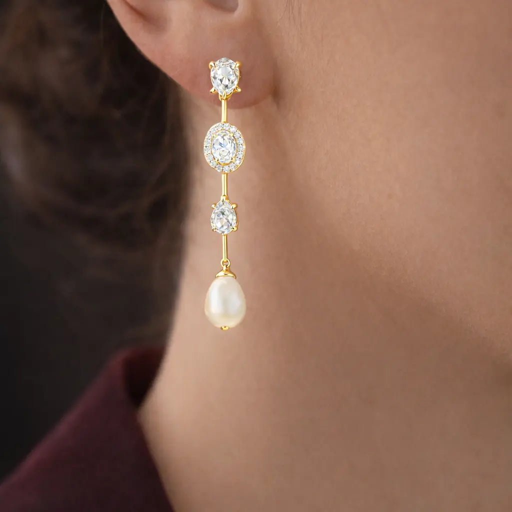 Gold earrings with pearls and gemstones worn by a person