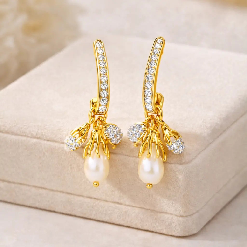 Gold earrings with pearls and crystals on a beige jewelry box