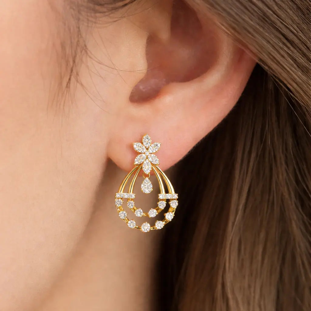 Gold hoop earring with floral design worn by a person