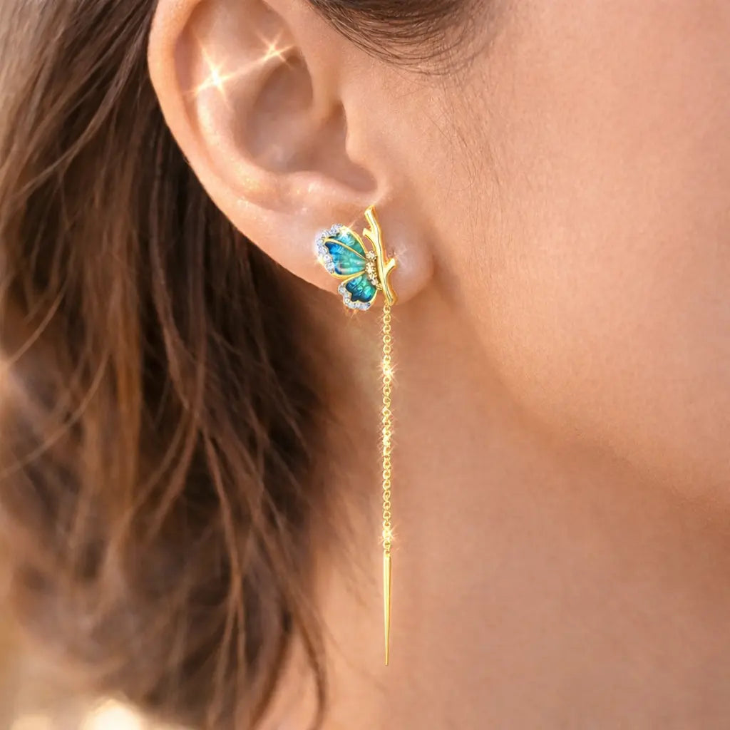 Butterfly-shaped earring with gold chain on a person's ear