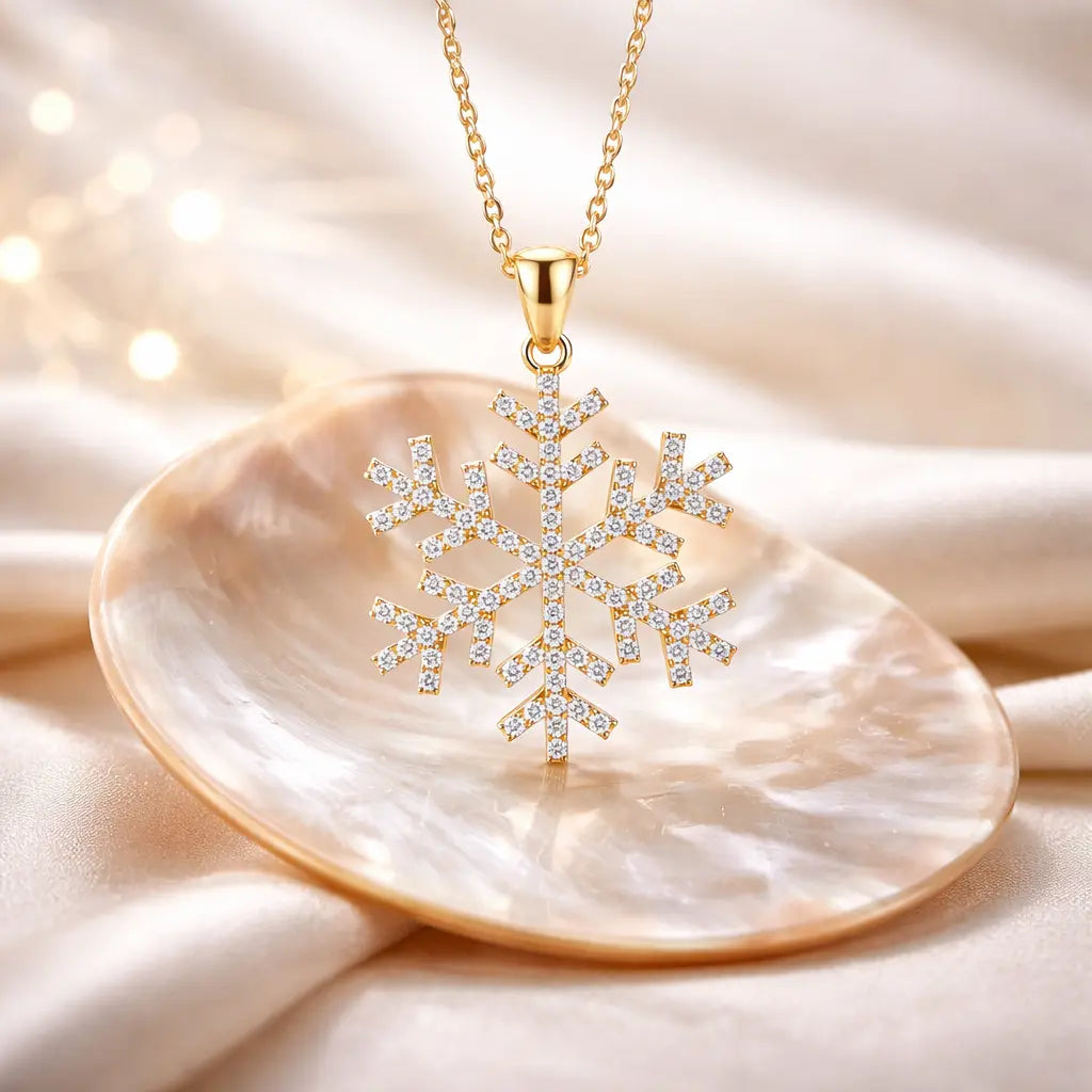 Gold snowflake pendant necklace on a shell with a soft beige background