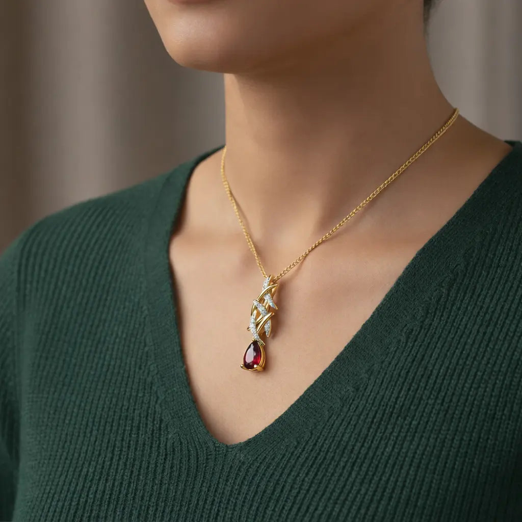 Gold necklace with a pendant worn by a person in a green sweater.