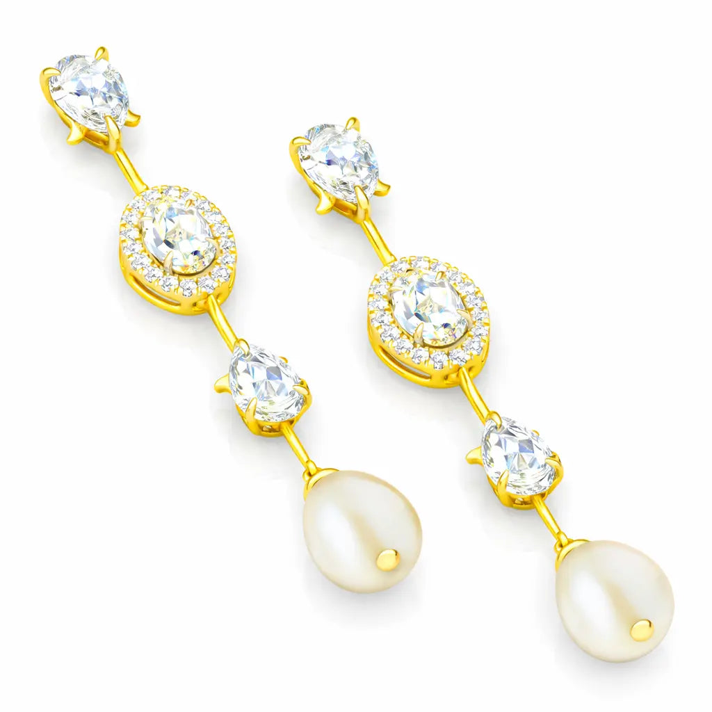 Gold earrings with clear gemstones and pearl-like drops on a white background