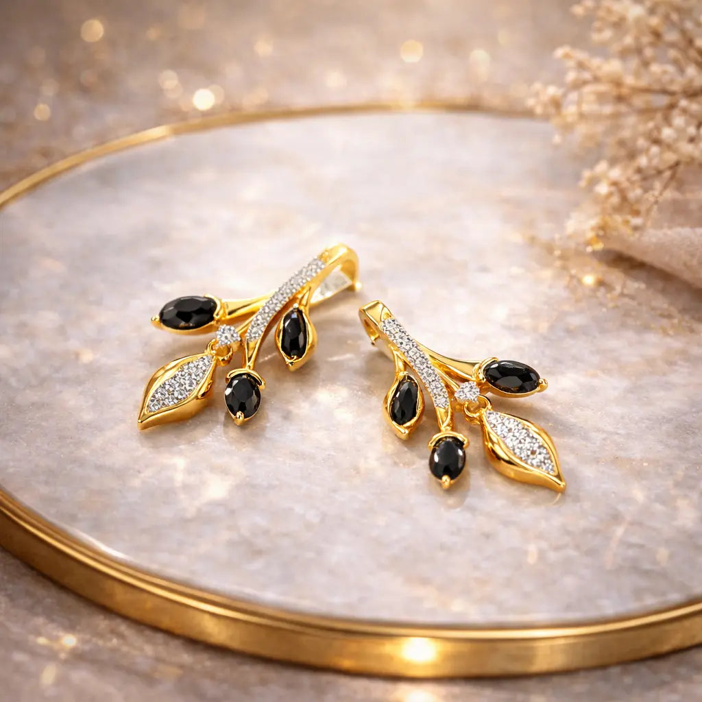 Gold earrings with black stones on a reflective surface
