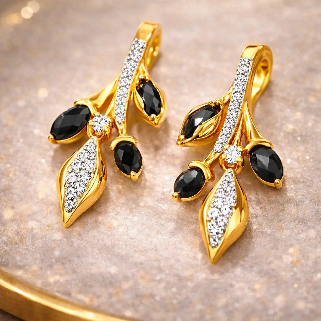 Gold earrings with black and clear gemstones on a reflective surface