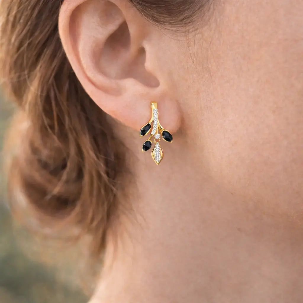 Gold earring with black stones worn by a person