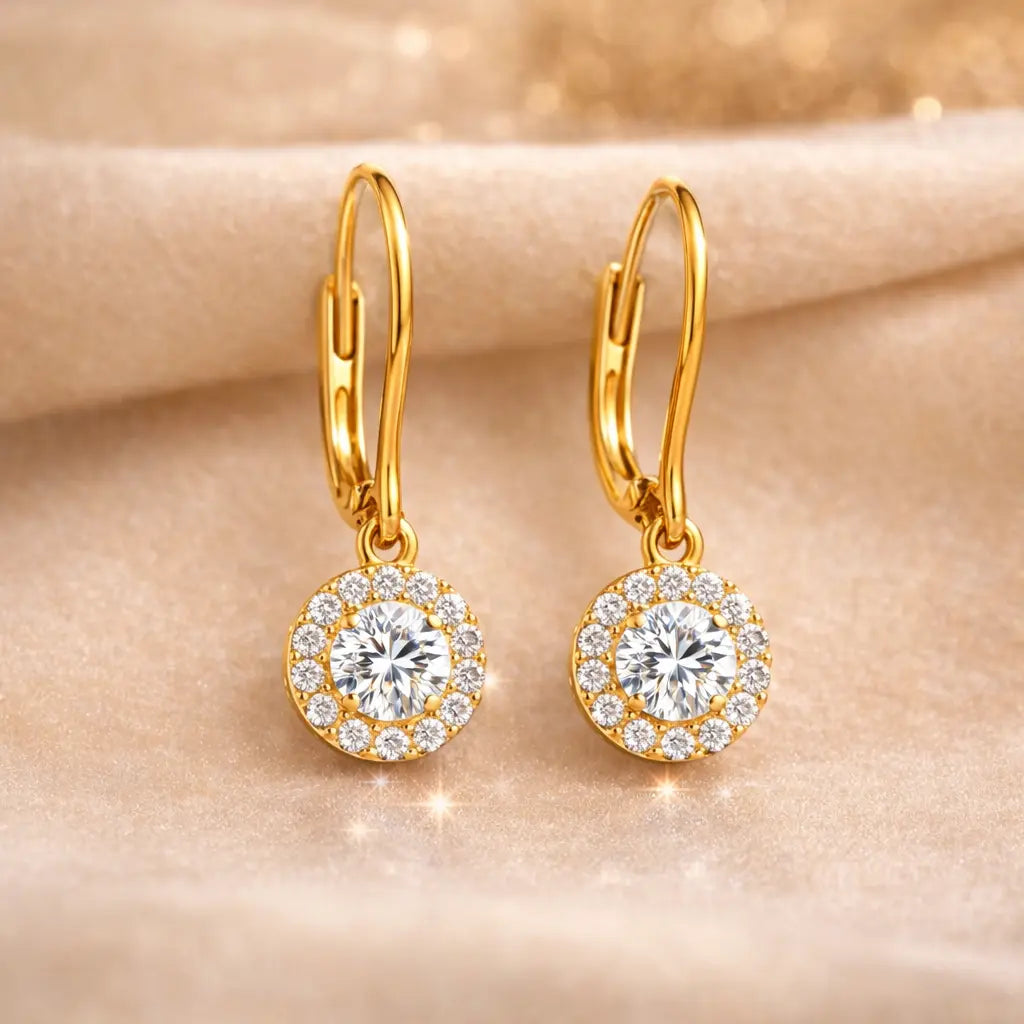 Gold earrings with clear gemstones on a beige background