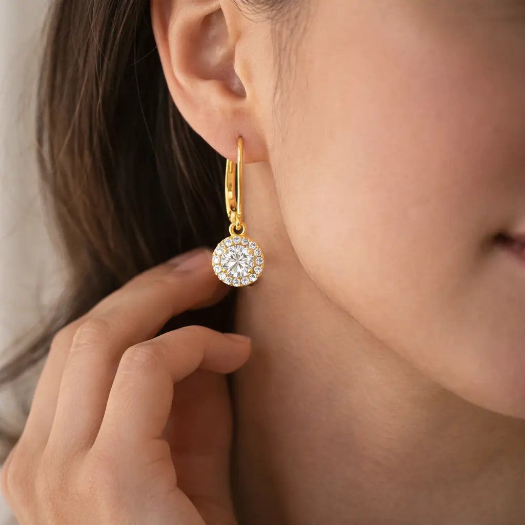 Gold earring with a diamond being worn by a person