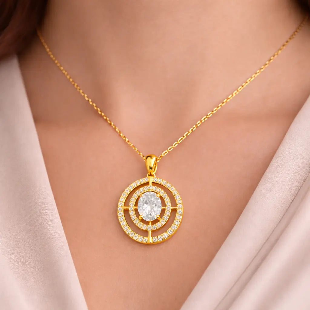 Gold necklace with a circular pendant featuring a diamond on a model wearing a light pink top.