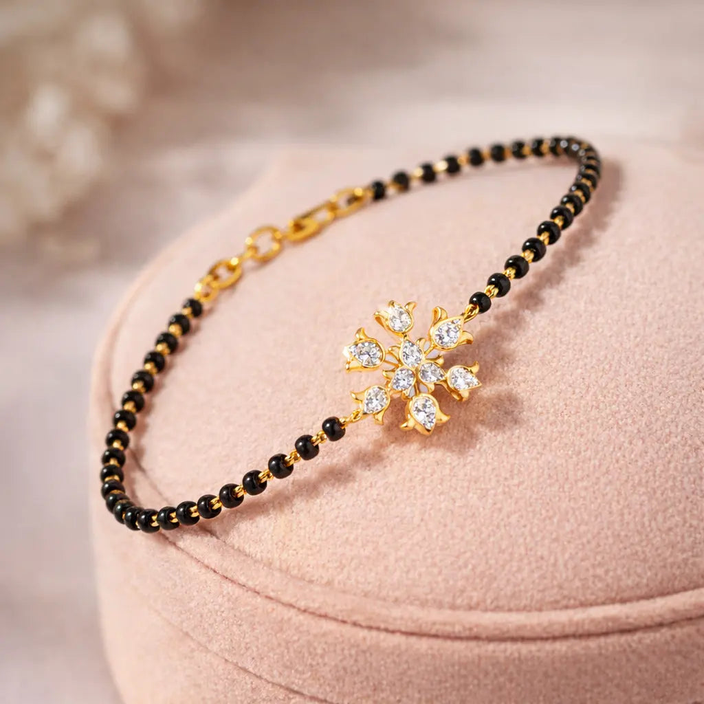 Gold and black beaded necklace with a decorative clasp on a pink cushion