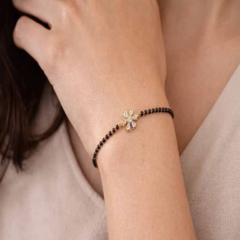 Bracelet with a snowflake charm on a wrist against a neutral background