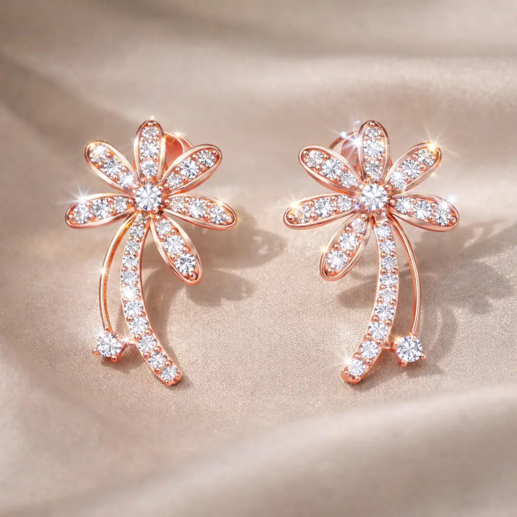 Rose gold flower-shaped earrings with clear gemstones on a beige fabric background