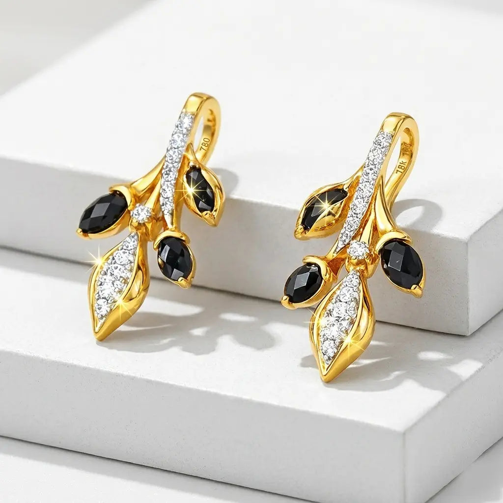 Gold earrings with black and clear gemstones on a white surface