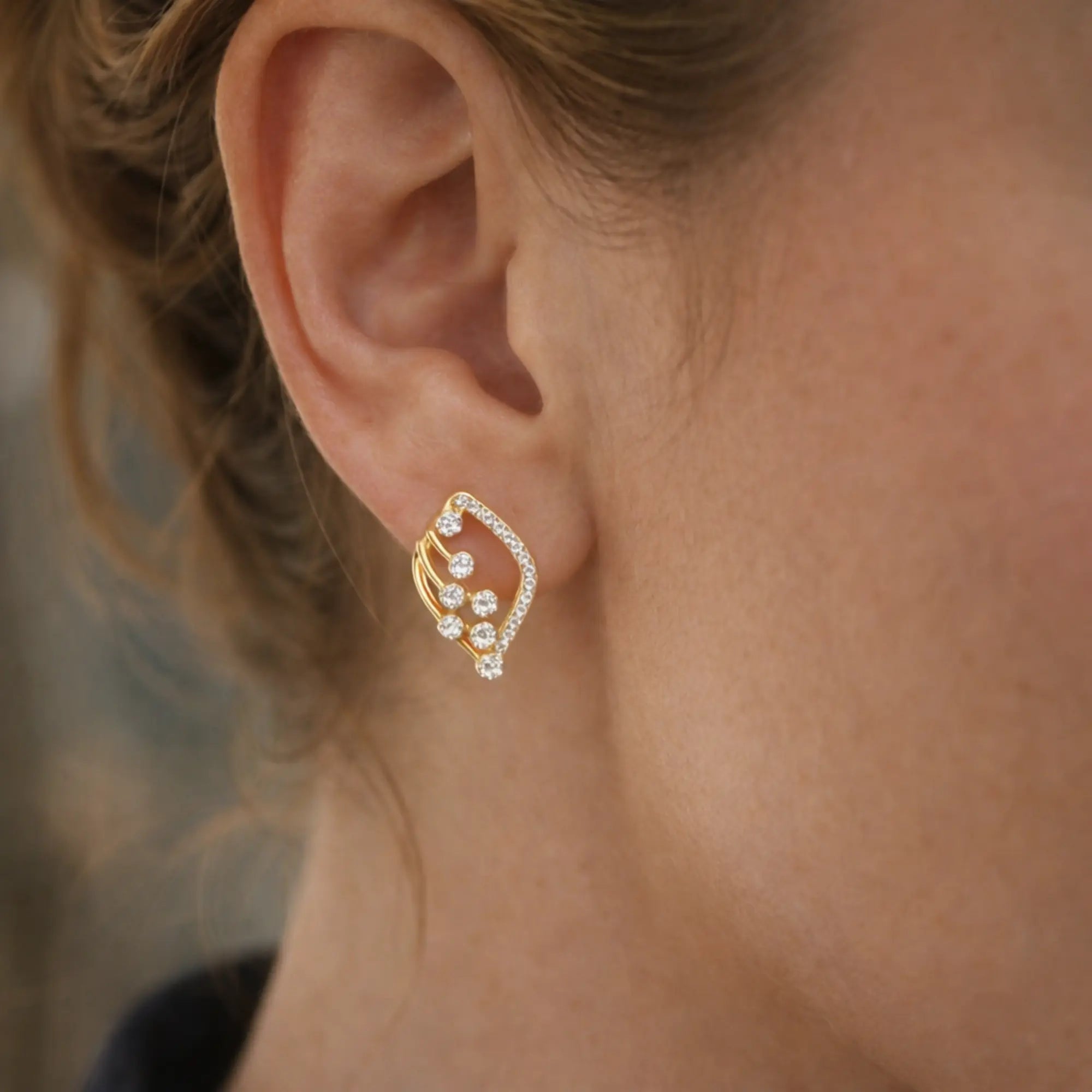 Close-up of a gold earring worn by a person with blurred background