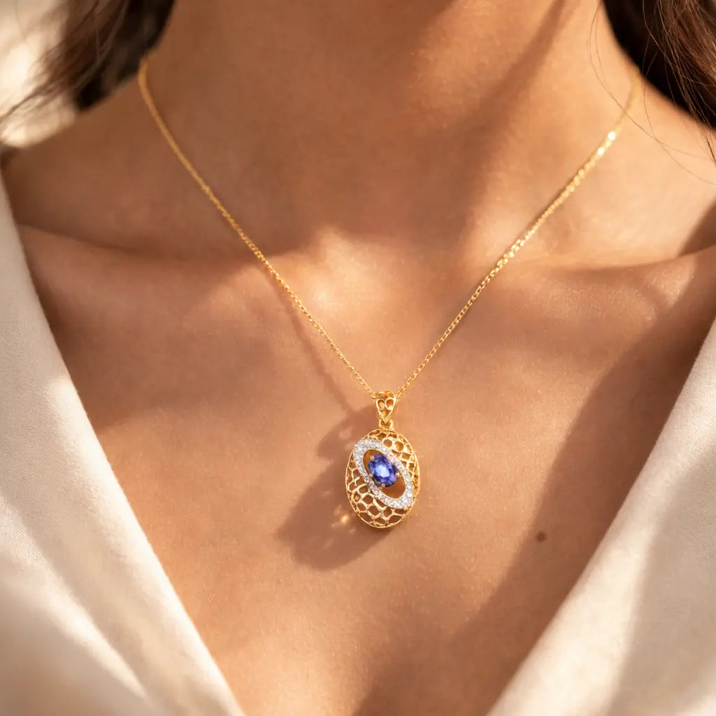 Gold necklace with a blue gemstone pendant on a person wearing a white top.